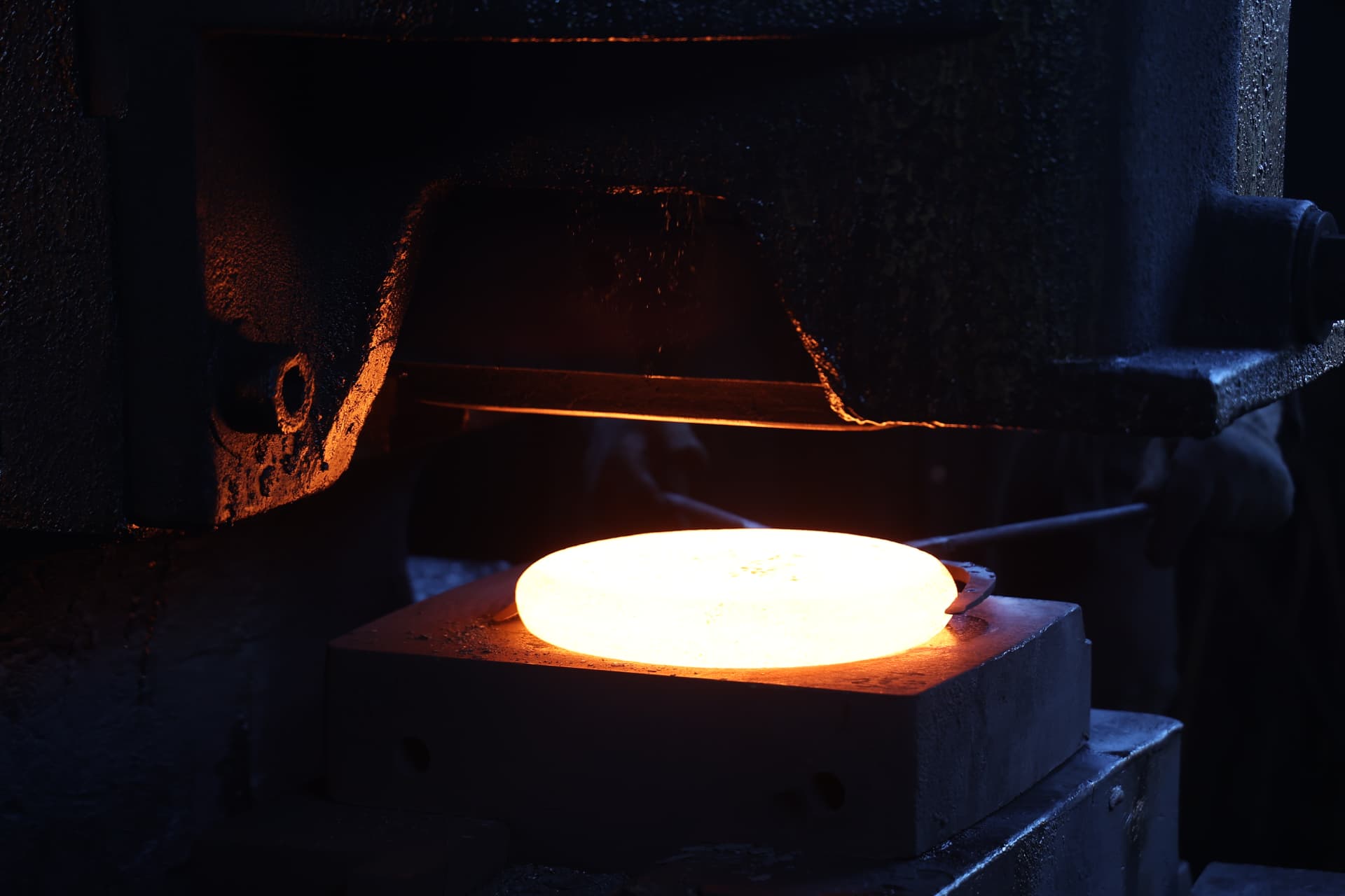 Glowing hot forged component on the die of a forging press at Hema Industries