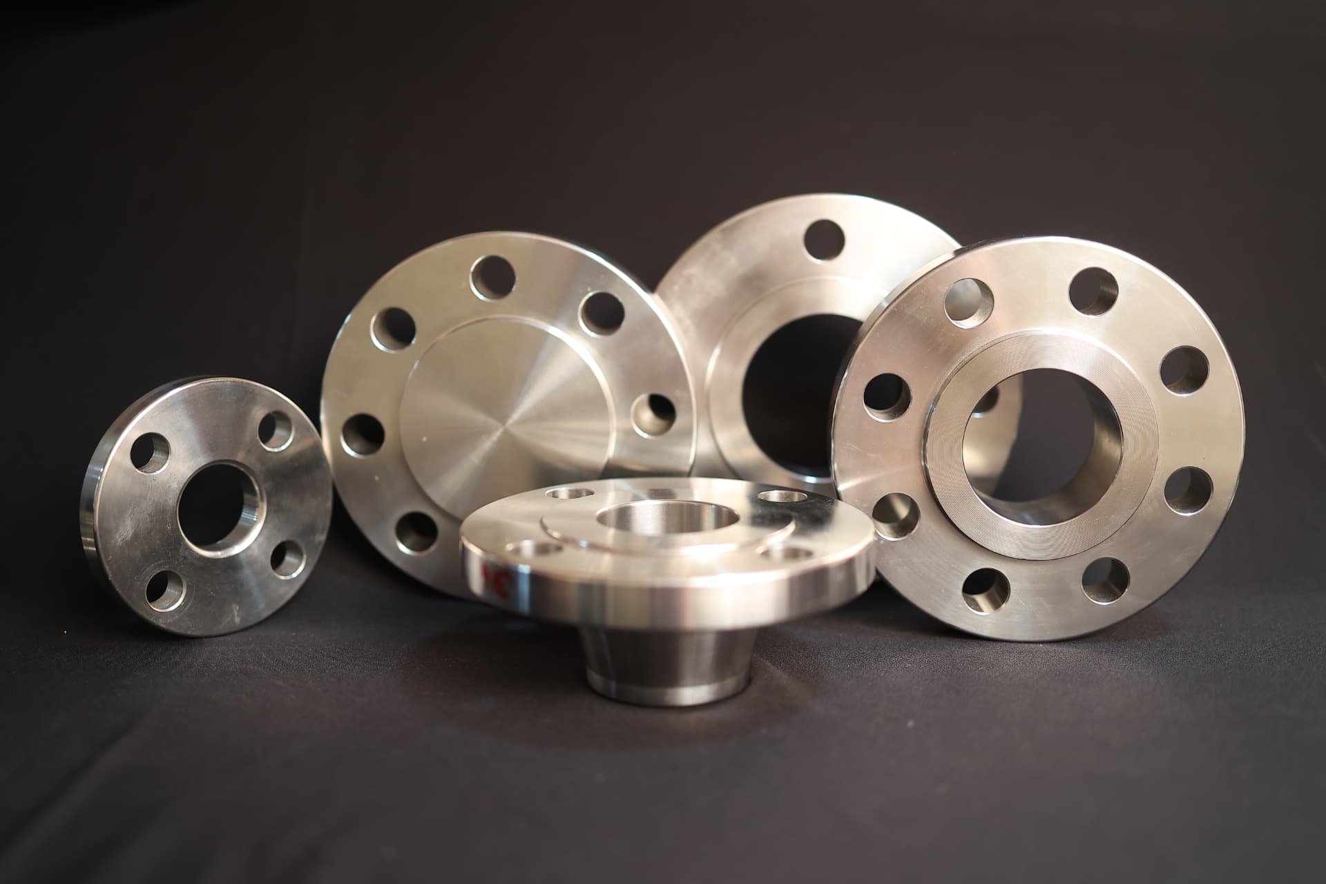 Machined steel flanges stacked on a dark workshop surface
